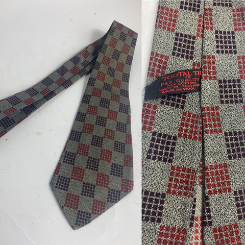 1940s Tootal tie in red quality label. Grey with black flecks and maroon and red segmented square pattern. No lining and open backs with short blade at 117cm long and 9cm wide. Slight asymmetric blade tip but no damage.