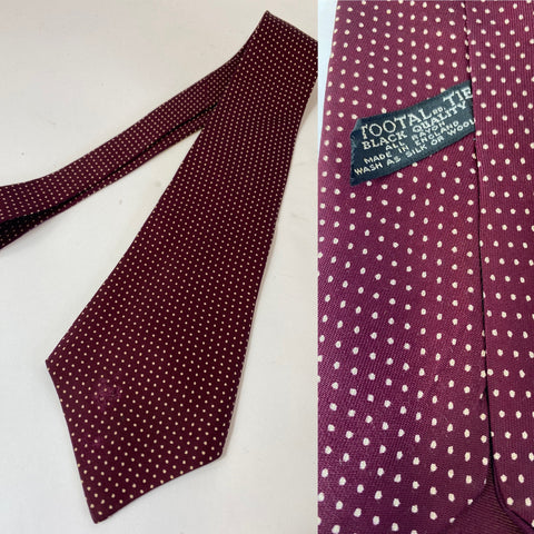 1940s/early 50s Tootal tie in black quality label. Maroon with white spots. Open backs and short blade at 128cm long 9cm wide. Slight fray mark on bottom front and tiny hole near middle thin end.
