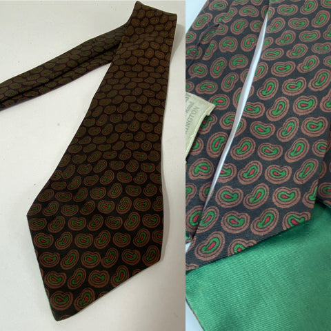 1950s British silk tie in black with green brown and red paisley motif pattern. Open backs and fairly short blade at 128cm long and 9cm wide. No damage.