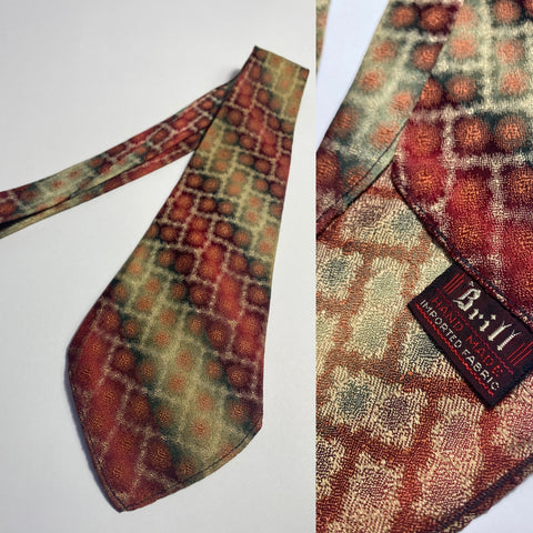 1930s tie,Brill, hand made in blended stripes red and green with an over laid geometric pattern. No lining and open backs with short blade at 120cm long and 9cm wide. No damage.