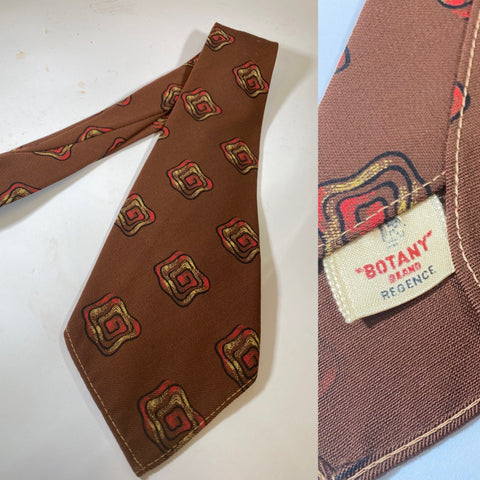1940s US swing tie, hand block printed. Botany brand label pattern. Chocolate brown with yellow red and black spiral motif pattern. No lining and open backs with short blade at 123cm - 10cm wide.