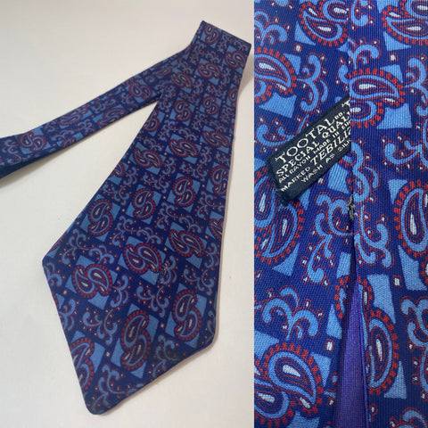 1940s Tootal tie special quality label in two tone blue with maroon paisley, geometric pattern. Open backs and short blade at 124cm long and 10cm wide. No damage.