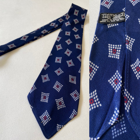 1940s Tootal tie in grey quality label. Navy blue with white and red geometric pattern. No lining, open backs and short blade at 124cm long and 8cm wide. No damage