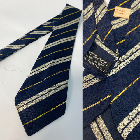 Early 50s British Silk tie in dark blue with silver and yellow stripe. No lining and open backs with fairly short blade at 130cm long and 8cm wide. No damage.