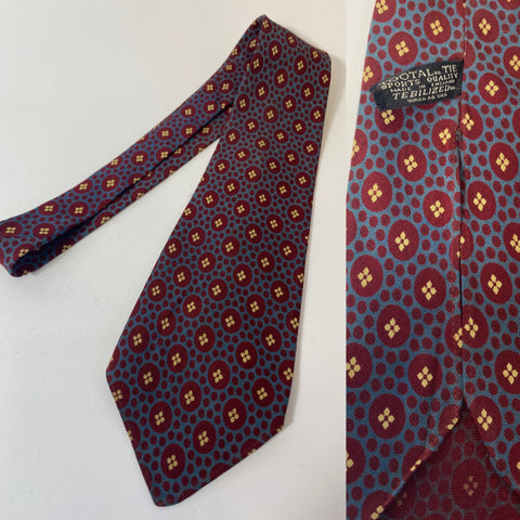 1940s Tootal tie in rare sports quality label. Blue with red and cream circular patterns. No lining and open backs with short blade at 120cm long and 9cm wide. No damage.