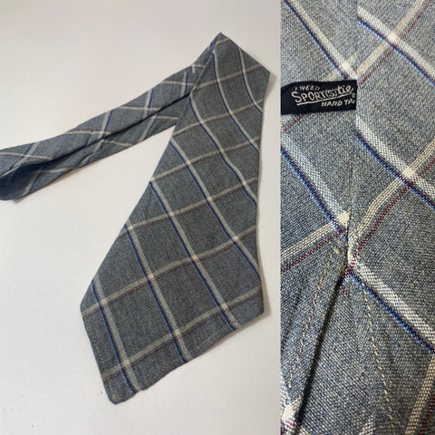 1940s sports tie, hand tailored in grey with blue red and white bow check. No lining, open backs and short blade at 113cm long 9cm wide. No damage.
