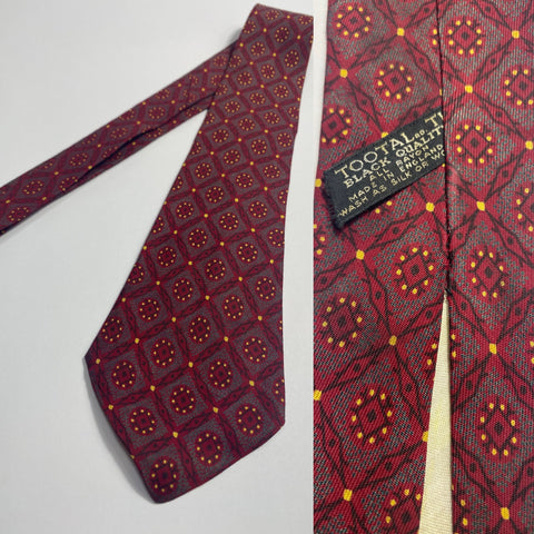 1950s Tootal tie in red and yellow pattern. Black quality label. Open backs and short blade at 130cm long 8cm wide. No damage.